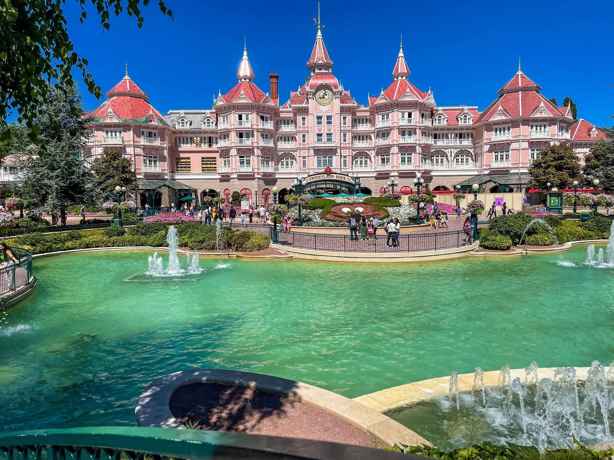 the entrance to the Disneyland Paris park in France with a pool of water in the foreground. 